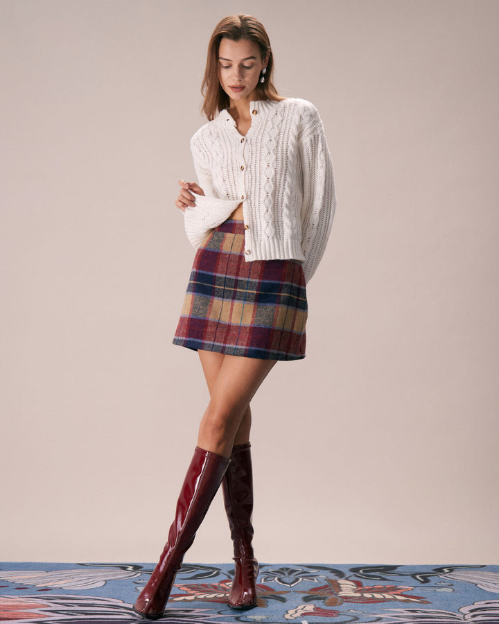 Full length view of a model in a red plaid mini skirt, cream sweater and red boots
