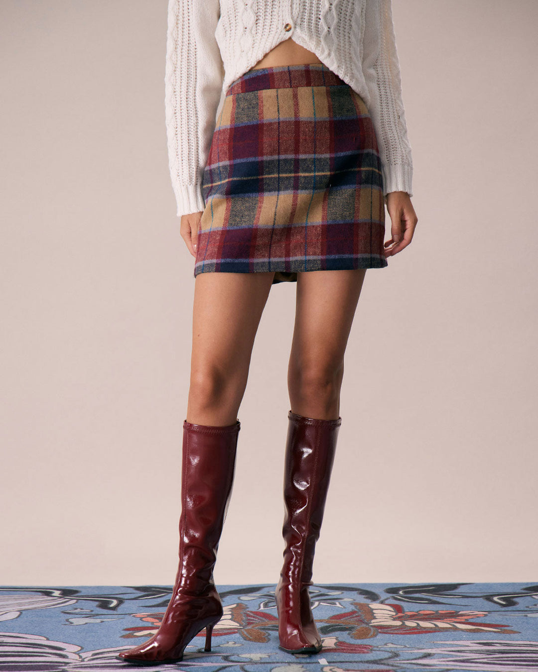 Red plaid mini skirt worn with a cream cable knit sweater and tall red boots