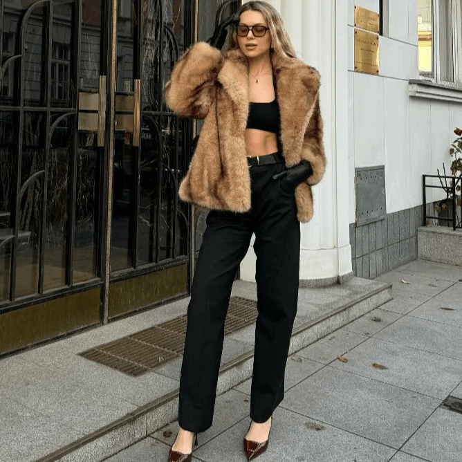 Front view of the caramel short faux fur coat worn over a black top and trousers