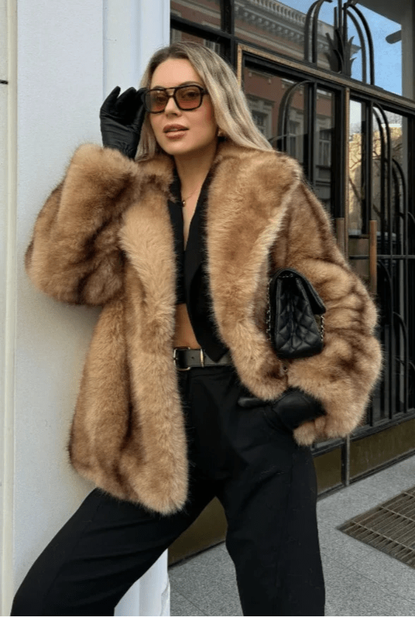 Model posing in the caramel oversized faux fur coat with hand on the lapel