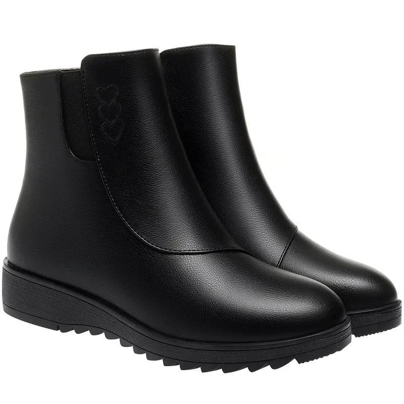 Black round toe flat ankle boots with treaded sole on a white background