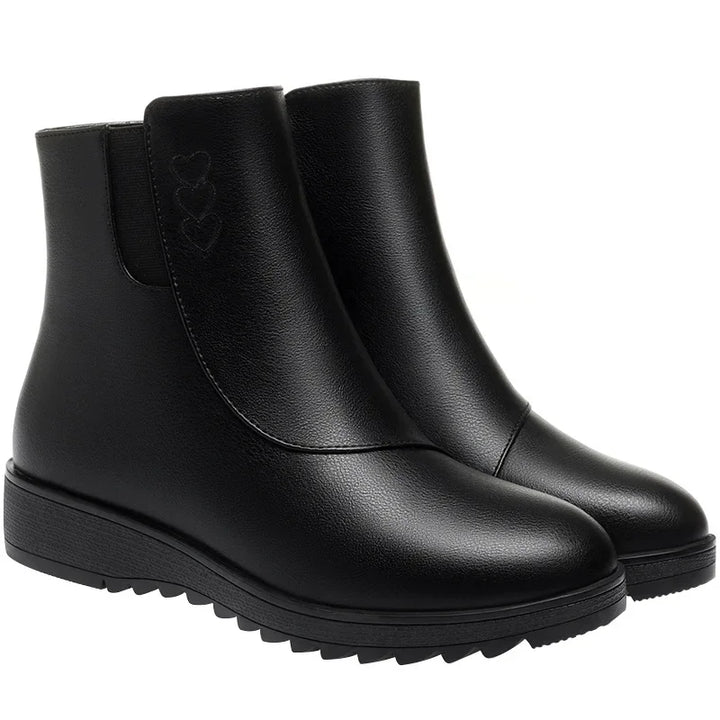 Black round toe flat ankle boots with treaded sole on a white background