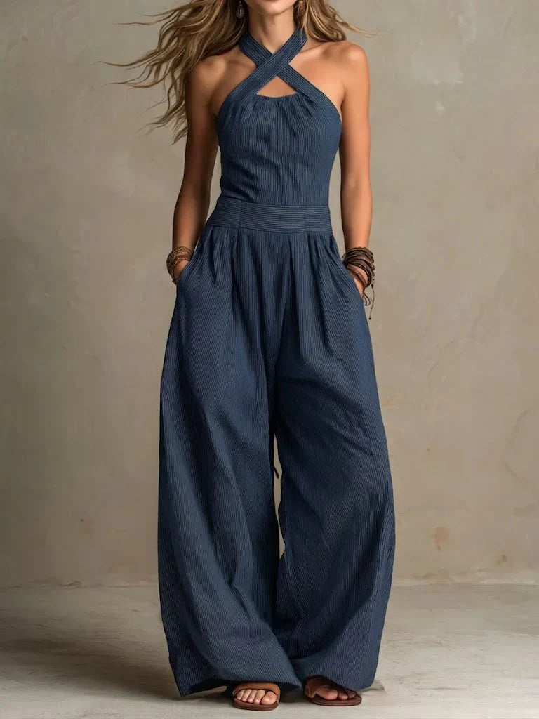 Navy crossover neck jumpsuit with wide leg and hands in pockets