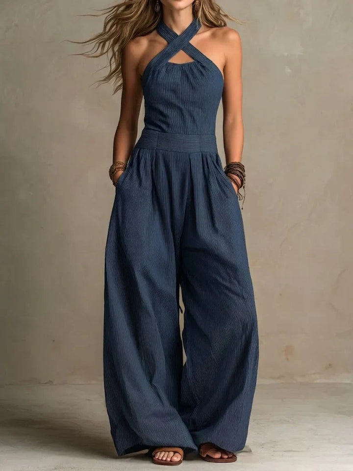 Navy crossover neck jumpsuit with wide leg and hands in pockets