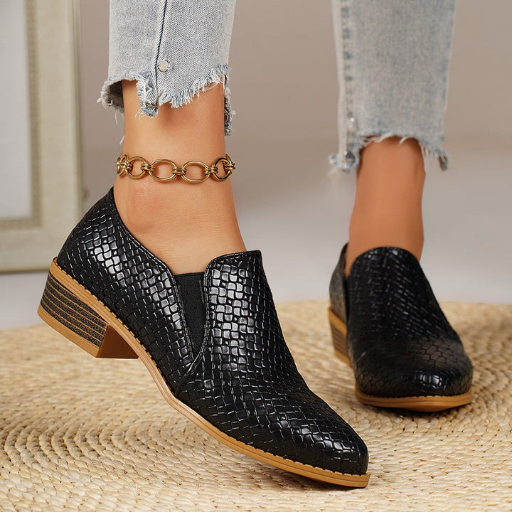 Black pointed toe loafers with low block heel, angled view on feet