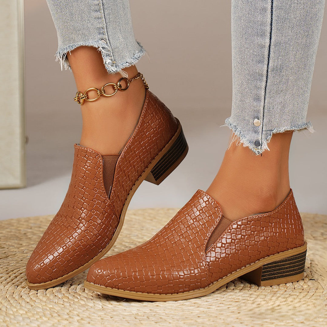 Pair of cognac heeled loafers with elastic side panels, worn with jeans
