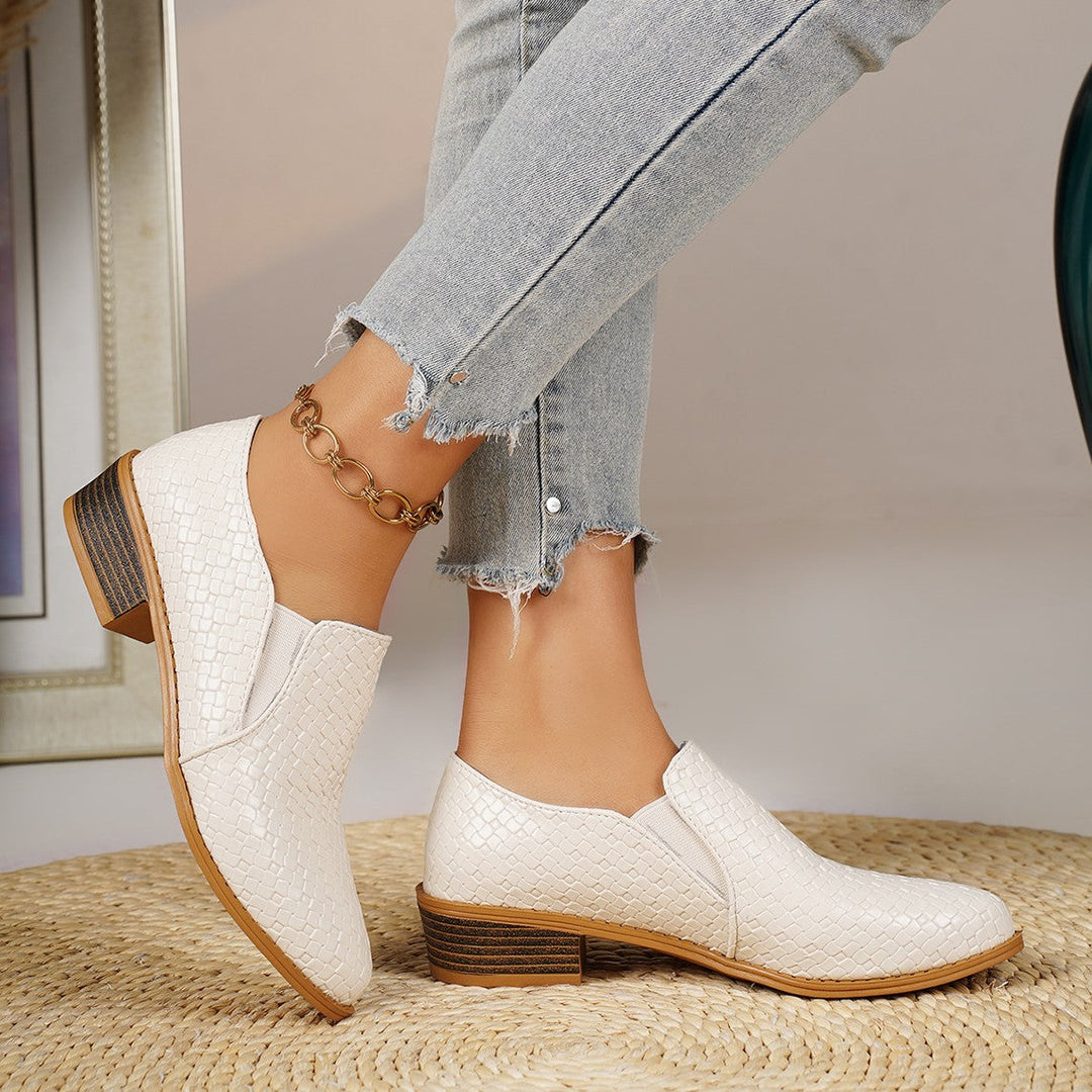 White slip on loafers pair, one shoe tilted to show the heel