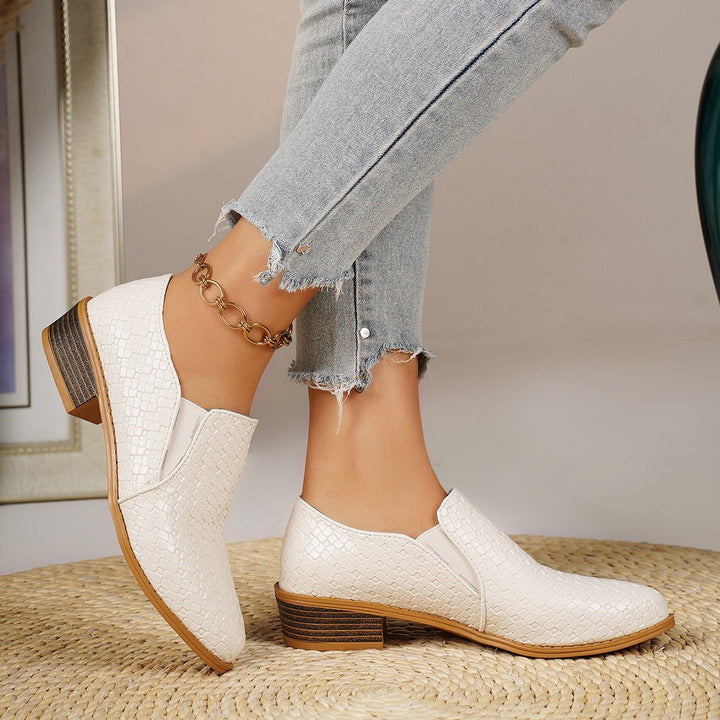 White slip on loafers pair, one shoe tilted to show the heel