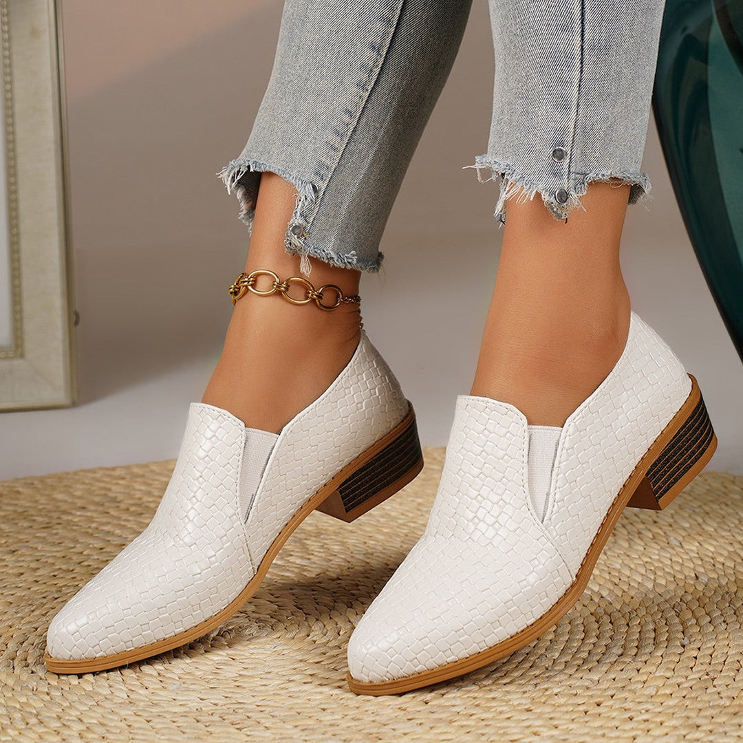White pointed toe loafers worn with cropped jeans, pair standing together