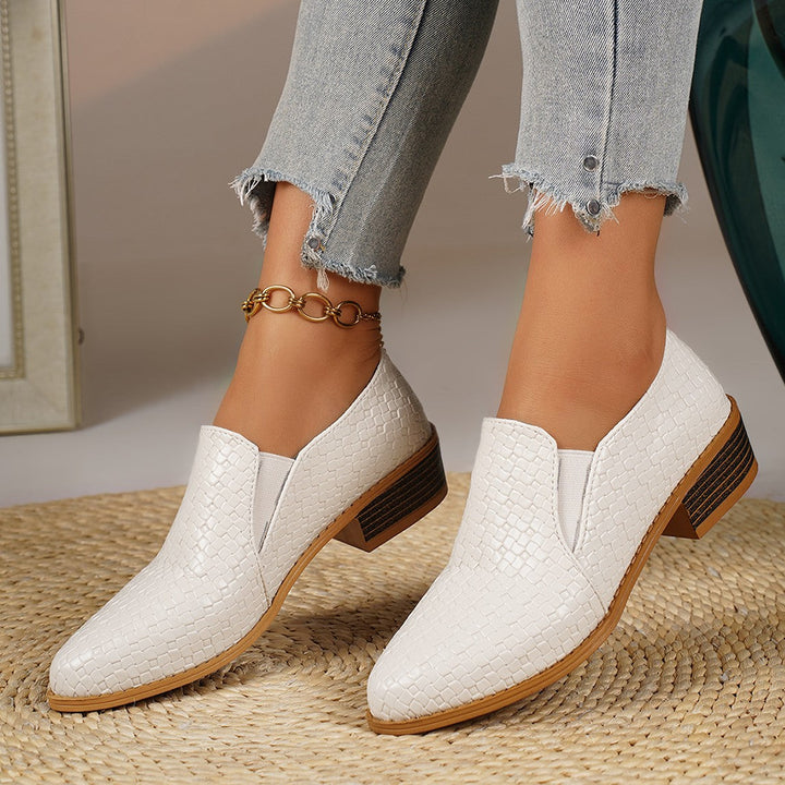 White pointed toe loafers worn with cropped jeans, pair standing together