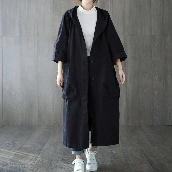 Black hooded trench coat worn open over a white top, front view
