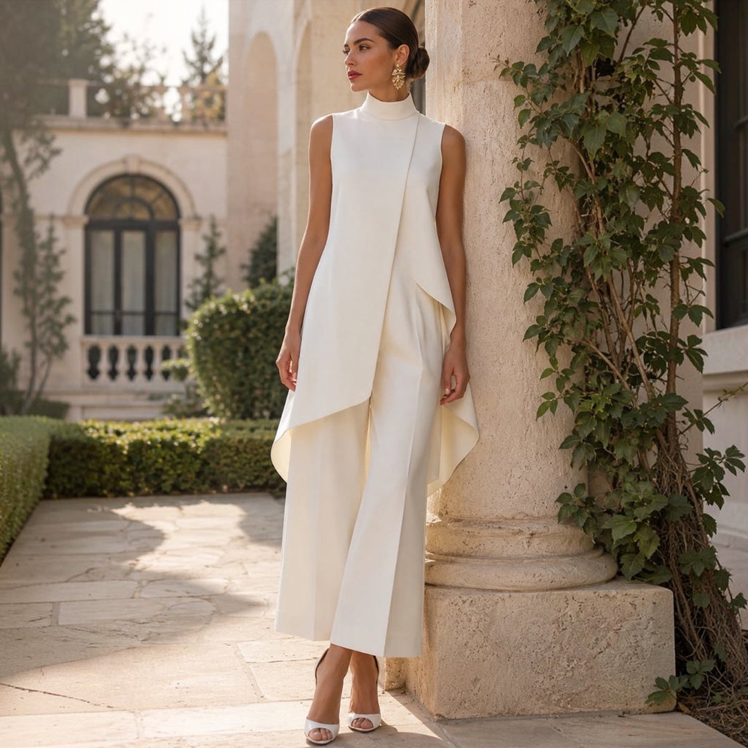 Ivory wide leg jumpsuit leaning on a stone pillar in a garden