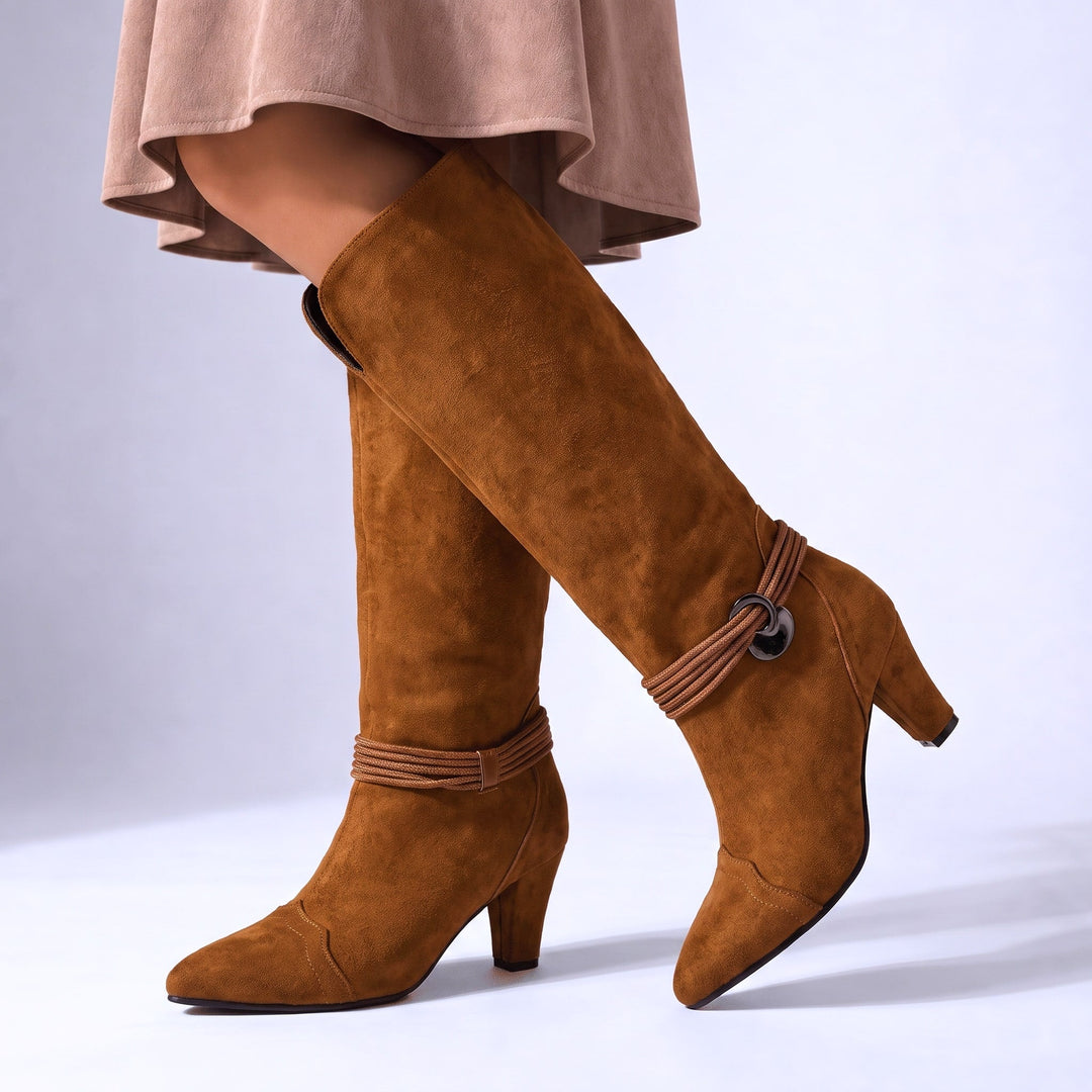 Tan suede-look knee high boots on a seated model, pointed toe with ankle strap