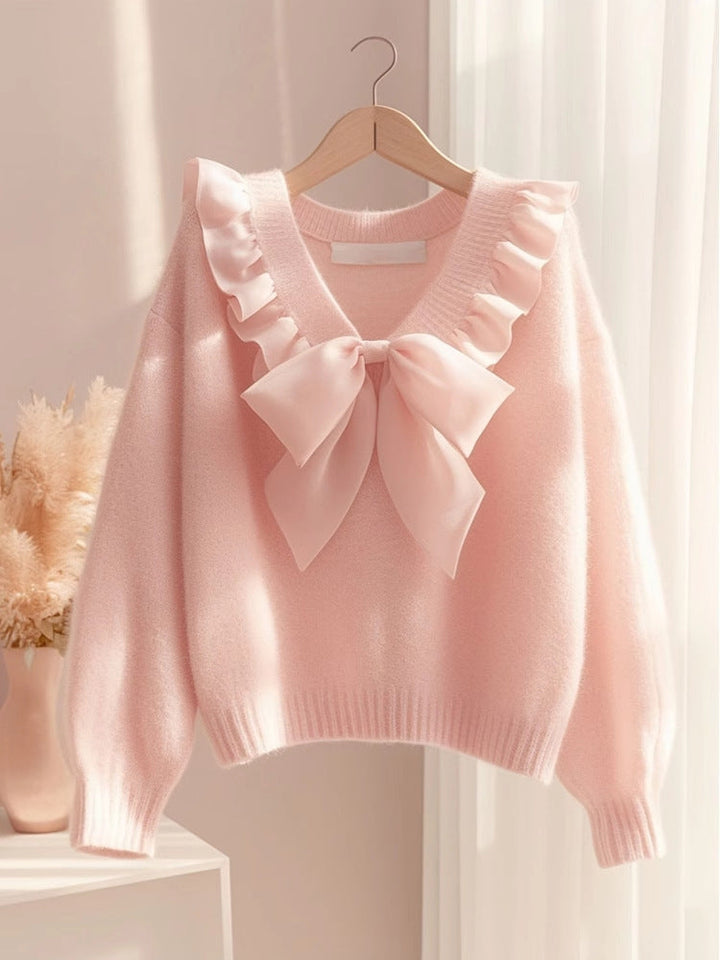 Pink bow sweater on a hanger showing the balloon sleeves and ribbed hem