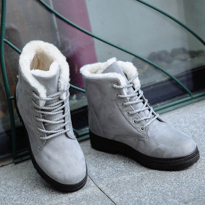 Pair of gray lace up snow boots photographed on a stone pavement