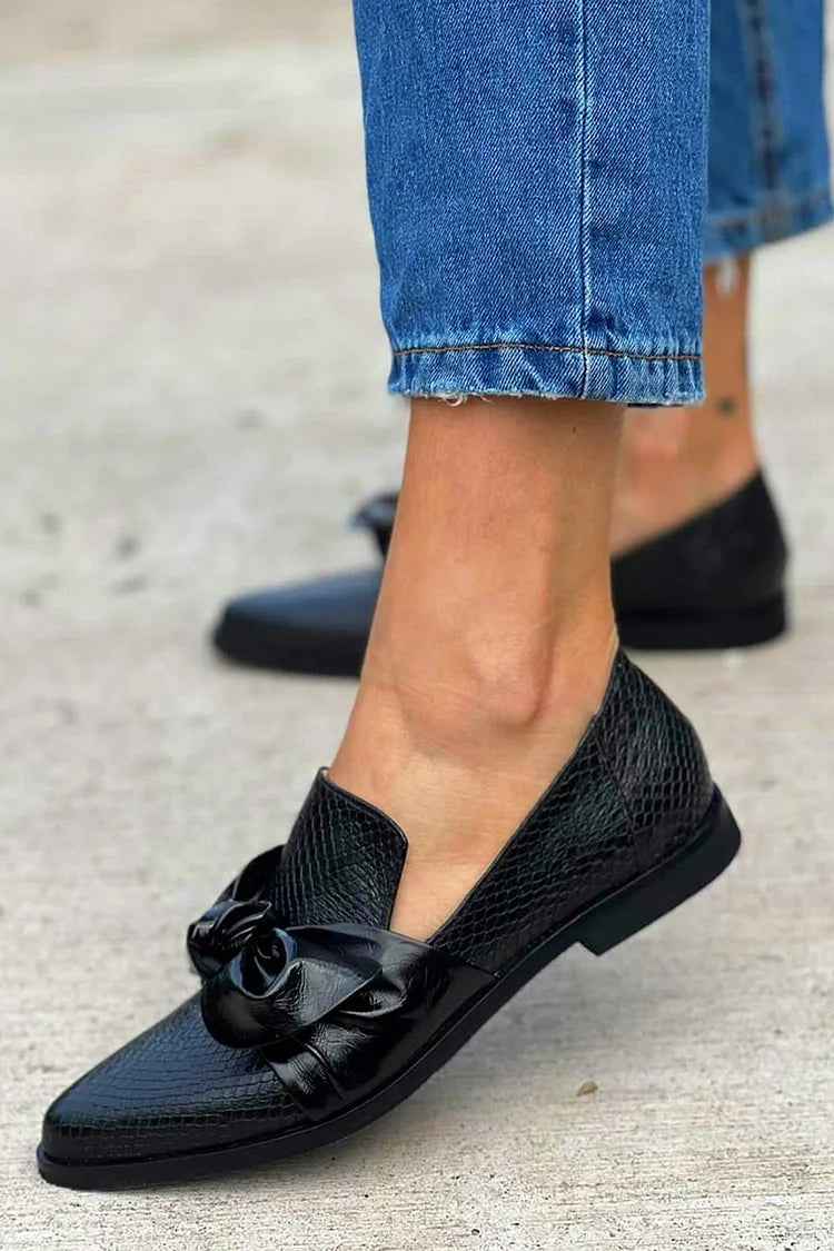 Side view of black pointed toe flat with a bow on the vamp