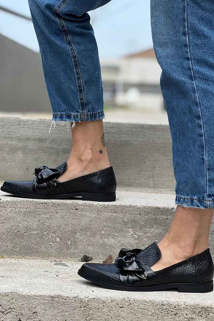 Black pointed toe flats with bow styled with frayed hem jeans on outdoor steps