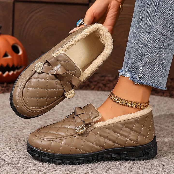 Coffee quilted loafer with bow detail held in hand