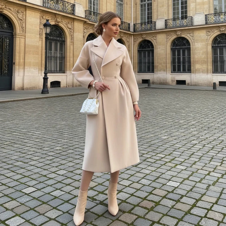 Woman in a beige double breasted long coat standing on a cobblestone square