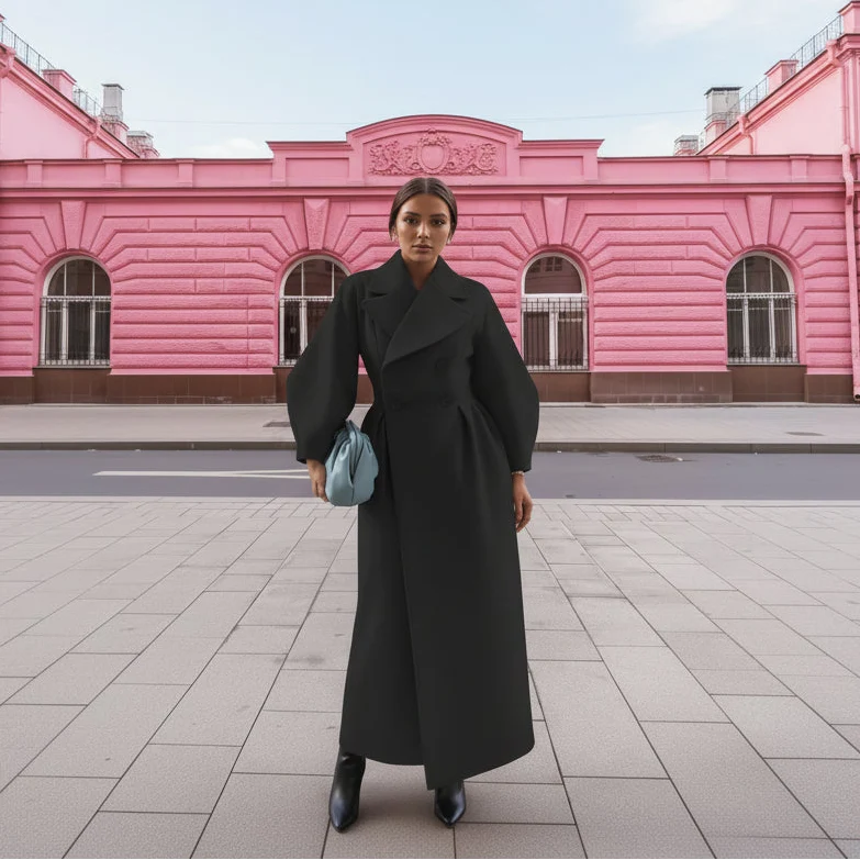 Black long coat with wide lapels and full sleeves in front of a pink building