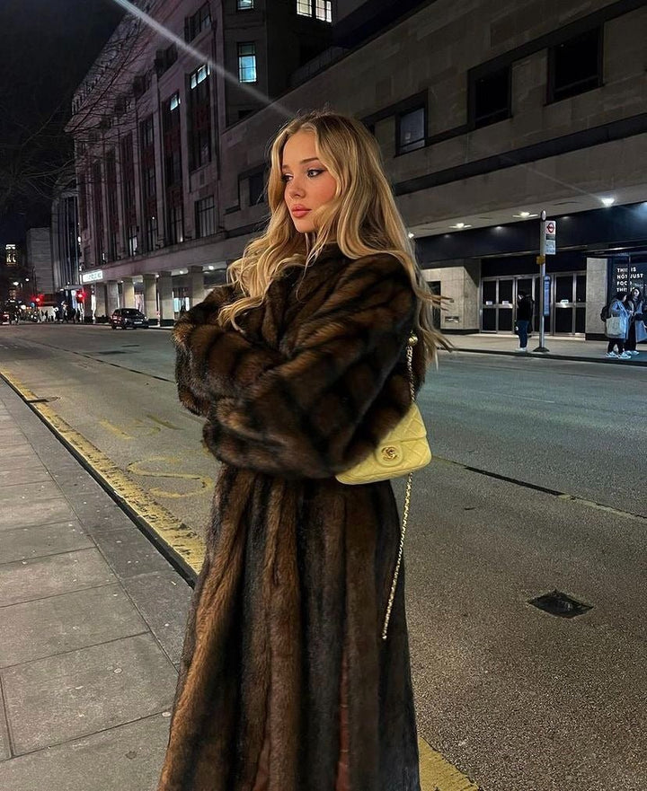 Model with long blonde hair in the dark brown faux fur coat on a city street