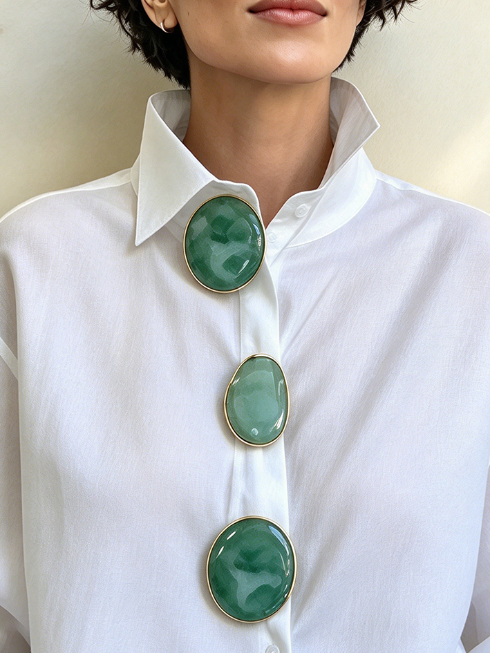 Close-up of the pointed collar and oval green buttons on the white shirt
