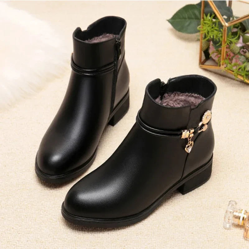 Pair of black low heel ankle boots with gold charm and side zip