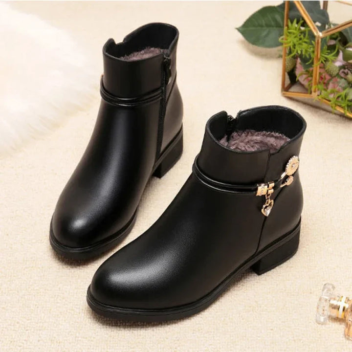 Pair of black low heel ankle boots with gold charm and side zip