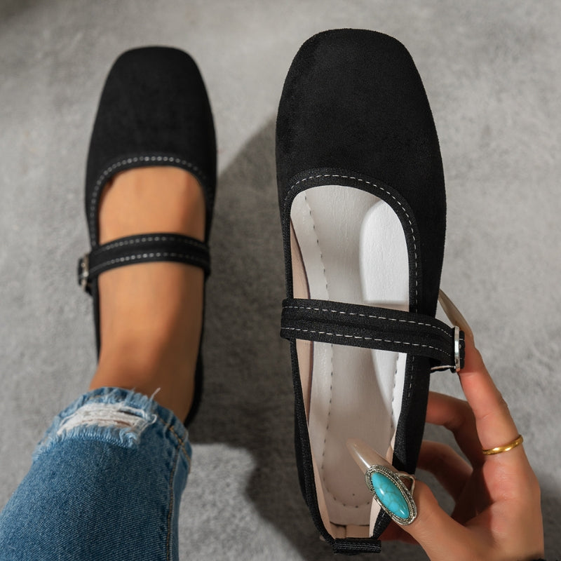 Top view of black Mary Jane flats with stitched edge and buckle, held in hand