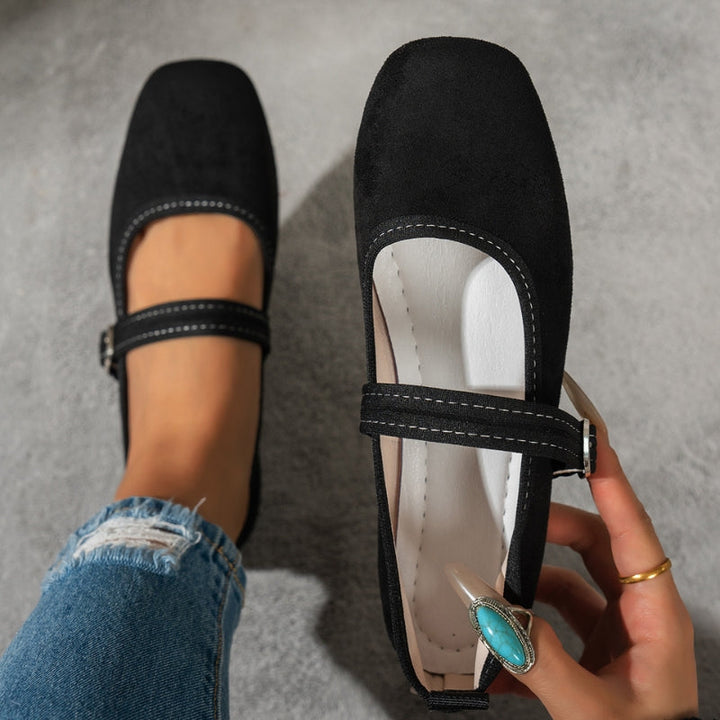 Top view of black Mary Jane flats with stitched edge and buckle, held in hand