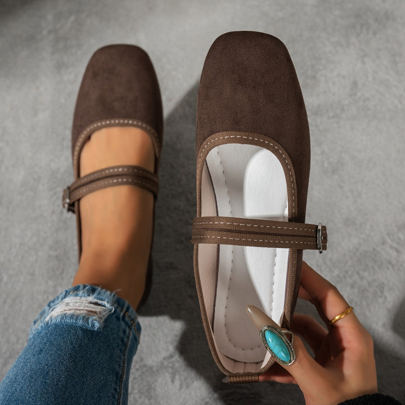 Dark brown suede look Mary Jane flats from above, held in hand with jeans