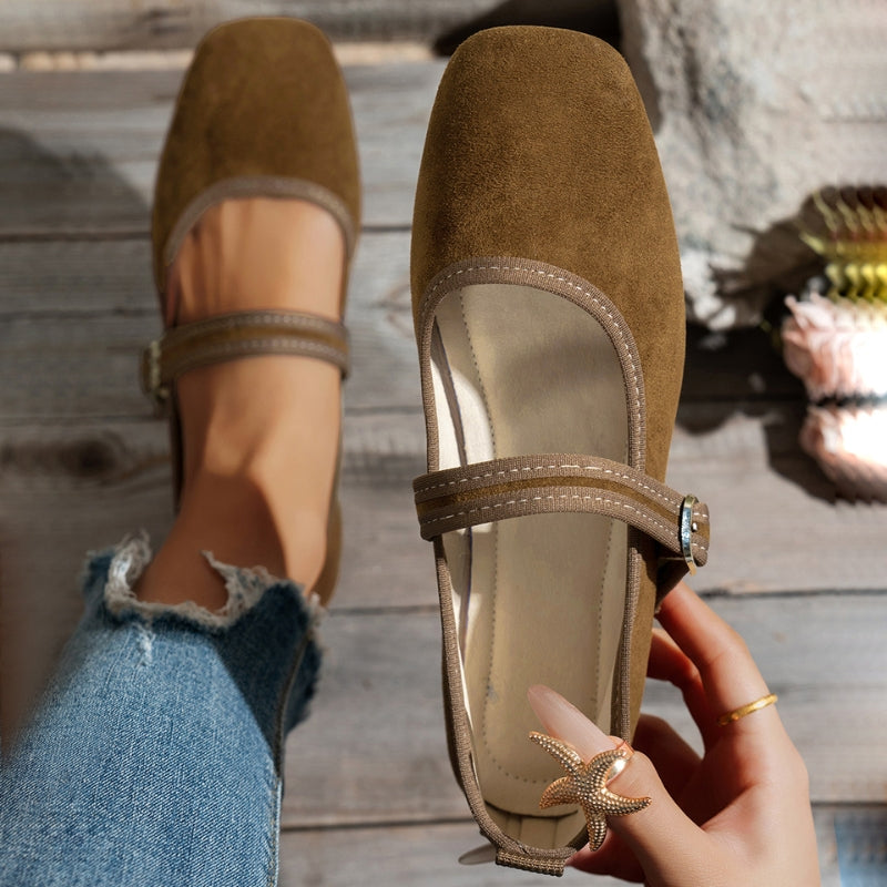 Khaki suede look flats seen from above, with strap buckle and cuffed jeans