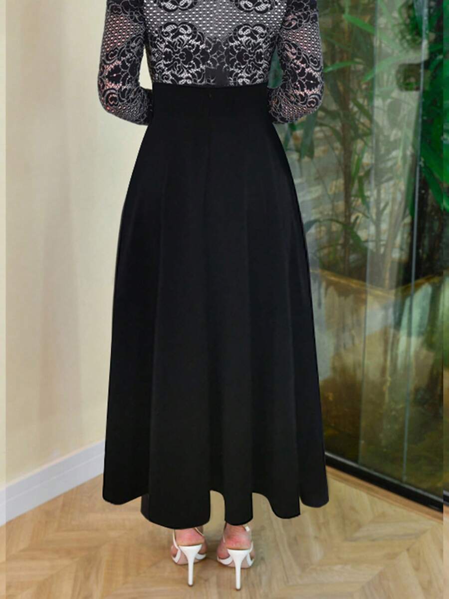 Black A-line maxi skirt worn with white strappy heels, front view