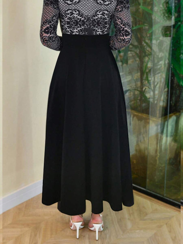 Black A-line maxi skirt worn with white strappy heels, front view