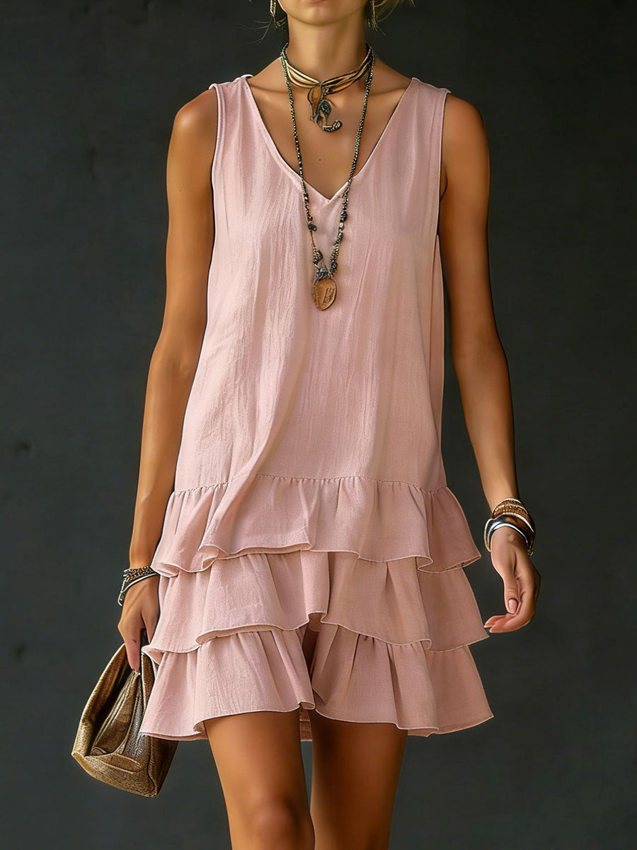 Pink sleeveless mini dress with three ruffle tiers and a beaded necklace