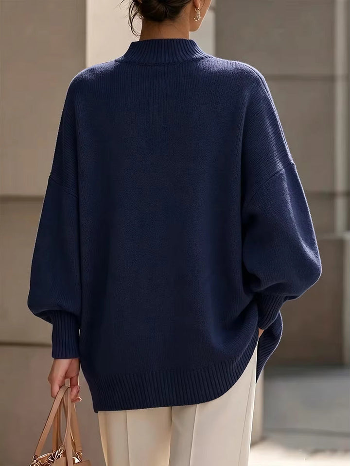 Back view of the navy oversized mock neck sweater with batwing sleeves on a model