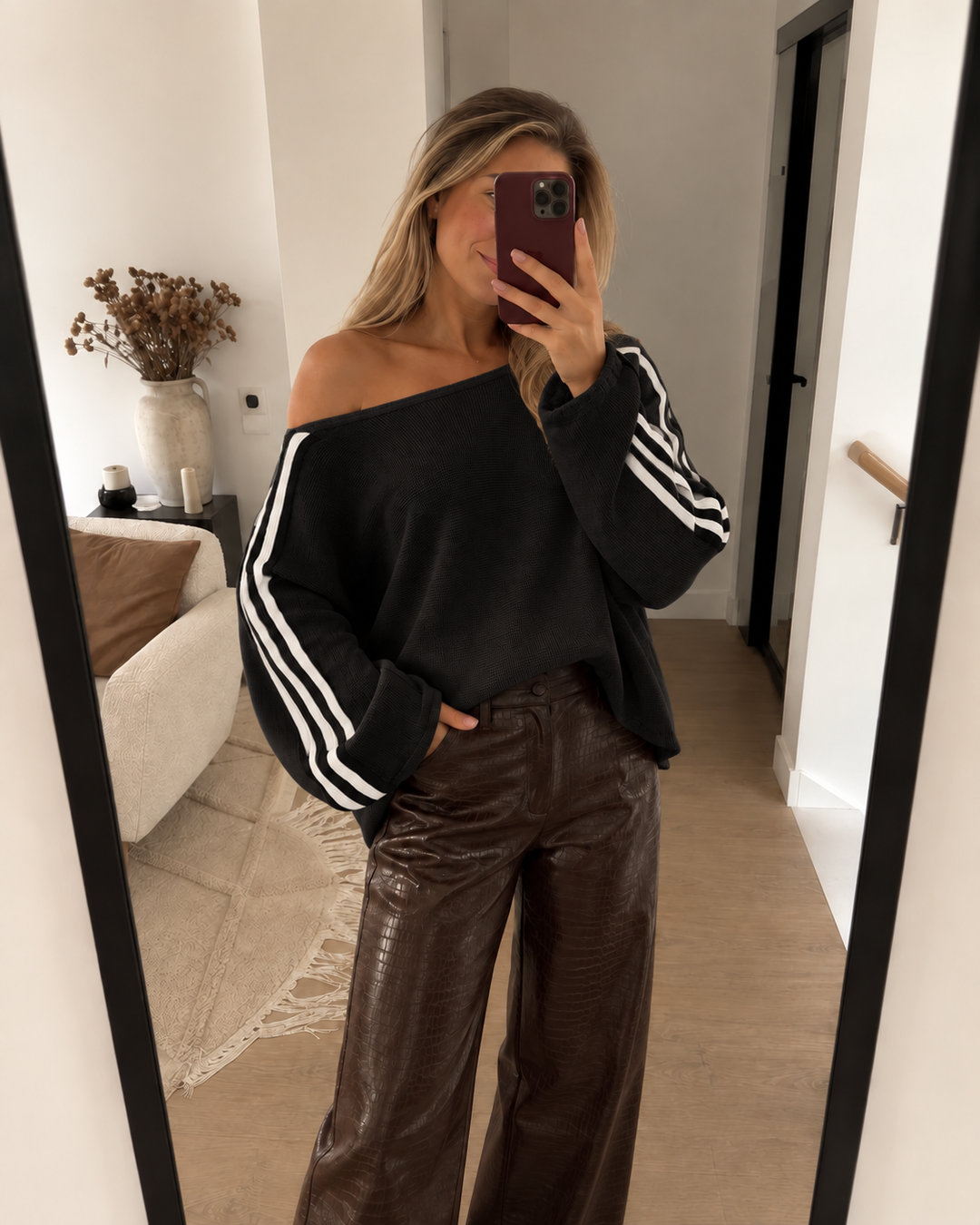 Black off shoulder sweater worn with brown leather pants in a mirror selfie