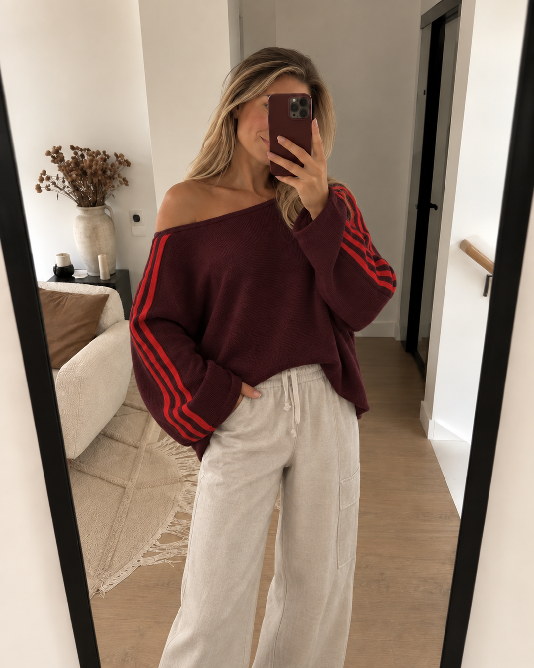 Burgundy striped sleeve sweater worn with cream pants in a mirror selfie