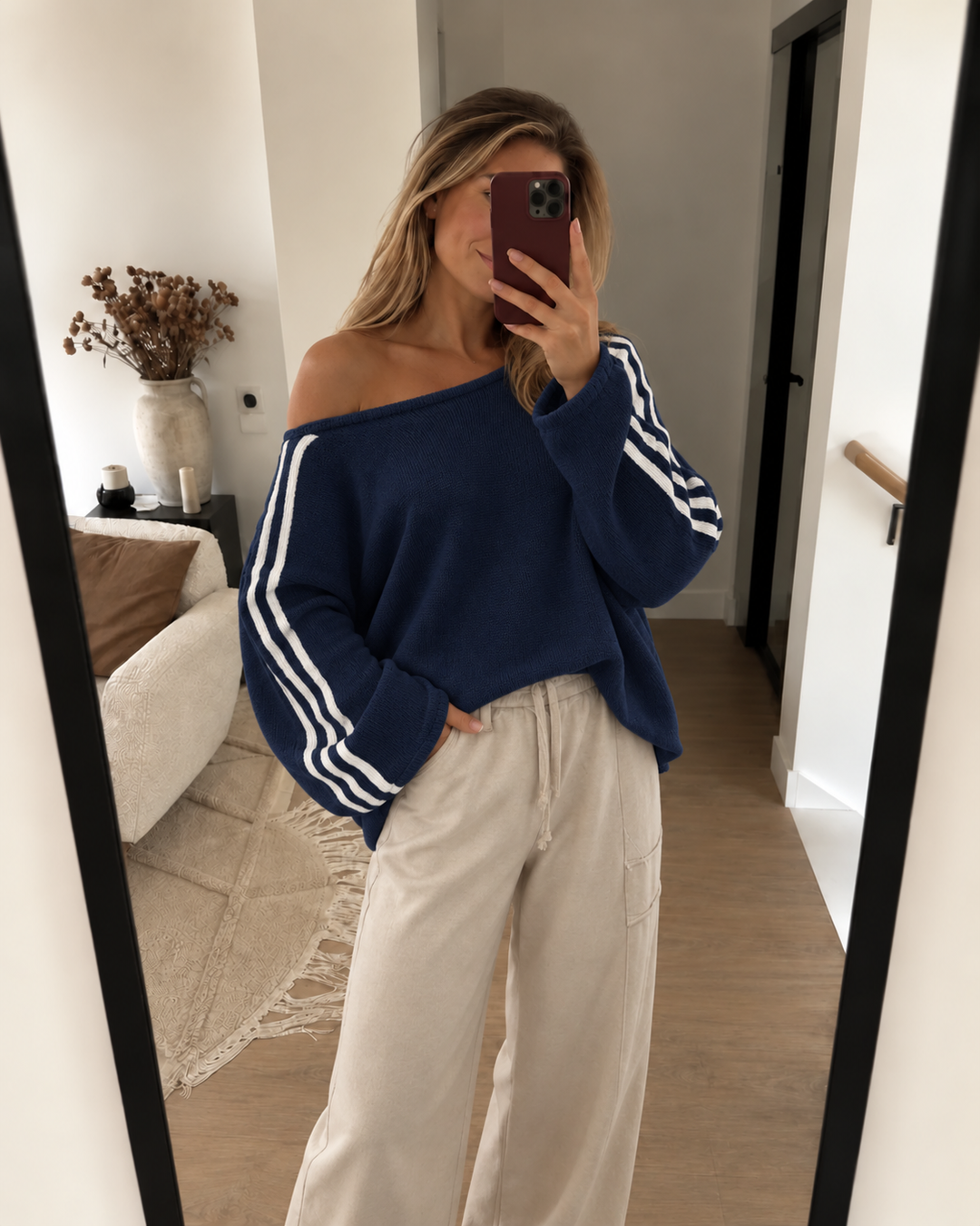 Navy off shoulder sweater worn with cream wide leg pants in a mirror selfie