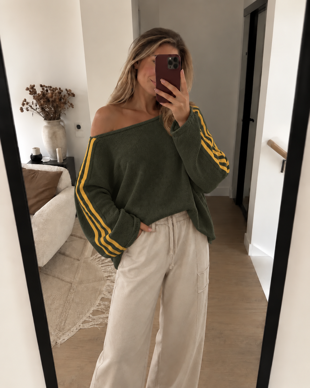 Olive off shoulder sweater with yellow striped sleeves and cream pants in a mirror selfie
