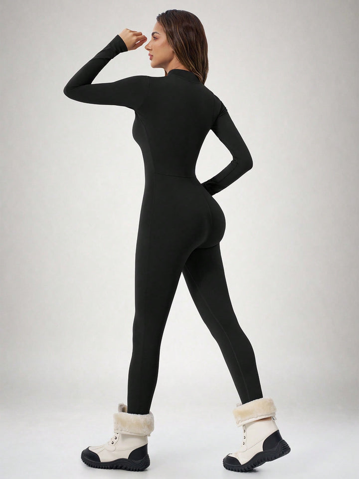 Back view of the black fitted ski suit with snow boots