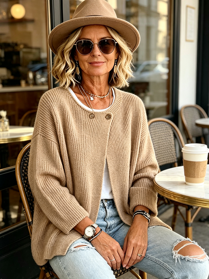 Camel cardigan styled with a felt hat and sunglasses at a cafe table