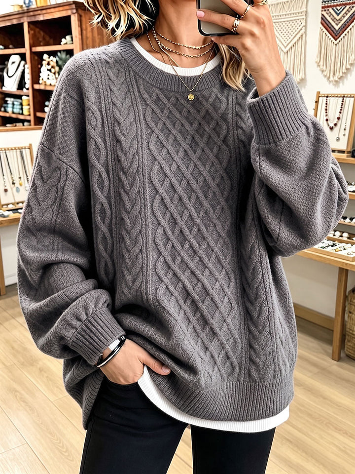 Gray oversized knit with diamond cable pattern falling past the hips