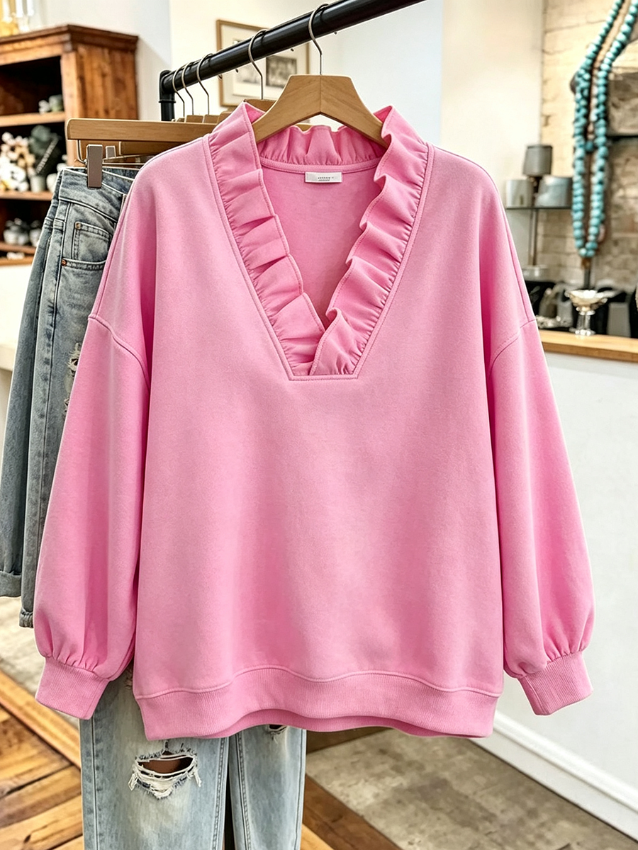 Pink ruffle neck sweatshirt on a hanger showing the relaxed shape