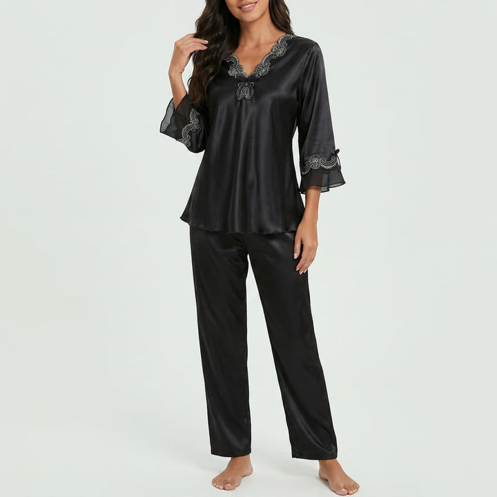 Woman wearing the black satin-look pajama set with lace trim, front view