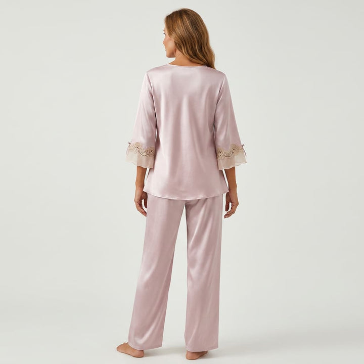 Back view of the light pink satin-look pajama set on a model