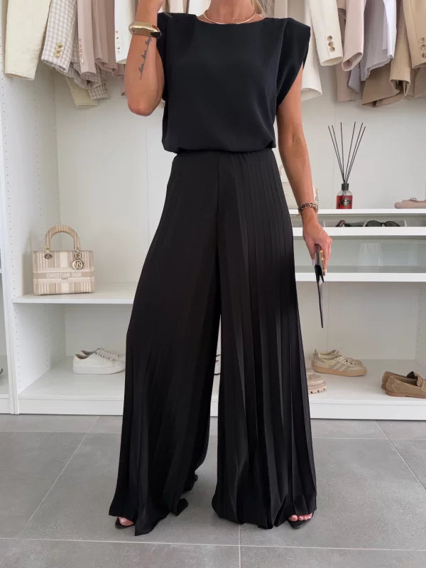 Close-up of the black sleeveless top tucked into high waisted pleated wide leg pants