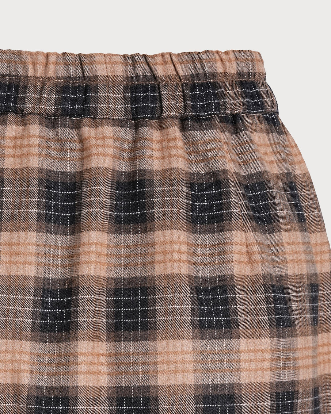 Detail of the elastic waistband and plaid pattern on the brown mini skirt