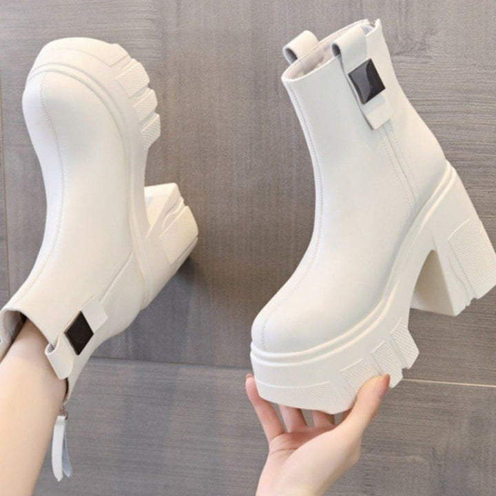 Off white chunky lug sole ankle boot held in a hand showing the back tab