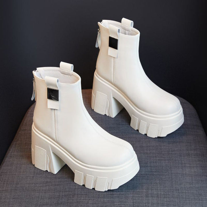 Pair of off white platform ankle boots with chunky lug sole on a gray fabric seat